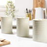 Set of three cream storage canisters labelled sugar, coffee and tea on kitchen worktop