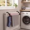 Black over-radiator drying rack holding socks and towels in a laundry room