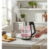 Glass electric kettle steaming on kitchen counter, shown with mug and sliced lemon