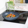 Speckled non-stick frying pan with stir-fried peppers and onions on induction hob