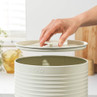 Cream bread bin with ridged sides, lid being lifted by hand