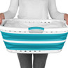 Teal and white collapsible laundry basket held by person in grey trousers