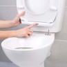 Person pressing quick release button on white toilet seat