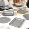 Set of non-stick metal roasting and baking trays on a kitchen counter