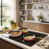 Set of three non-stick frying pans with gold handles on induction hob, eggs, stew, vegetables