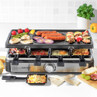 Salter raclette grill with hot plate, featuring assorted meats, vegetables and cheese pans, shown in kitchen setting