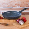 Non-stick black frying pan with speckled finish on kitchen worktop