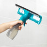 Hand using blue window vacuum spray and wiper to clean glass shower screen
