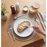 Breakfast scene with buttered sourdough toast, silver cutlery and tableware on wooden table
