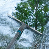 Grey and blue window squeegee cleaning soapy glass, outdoor use shown.