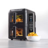Black dual air fryer oven with digital display, cooking chips and chicken, bowl of chips beside.