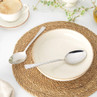 Set of two stainless steel dessert spoons on woven placemat with bowl