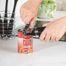 Opening a tin of pizza sauce with a black-handled can opener on a kitchen counter