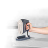 Hand holding a silver steam iron above folded fabric on an ironing board