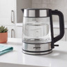 Glass and stainless steel electric kettle with water level markings on kitchen counter