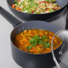 Non-stick saucepan with vegetable curry and coriander garnish, shown on kitchen surface