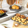 Non-stick roasting trays with grilled vegetables and whole roast chicken on kitchen counter