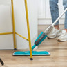 Blue spray mop cleaning wood floor near furniture, shown in use