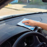 Hand using blue microfibre cloth to clean a car dashboard interior