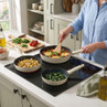 Set of three cream frying pans cooking eggs, potatoes and greens on modern hob