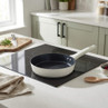 Cream non-stick frying pan on induction hob in modern kitchen