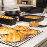 Black bakeware with pastries and cake on kitchen counter, ideal for home baking.