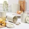Set of cream kitchen storage canisters for tea, coffee, and sugar on marble countertop