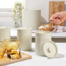 Set of cream kitchen canisters for coffee, tea and sugar on a counter, with hand using spoon