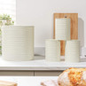 Cream kitchen canisters for bread, sugar, coffee and tea on a countertop