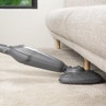 Silver steam mop cleaning under beige sofa on carpet