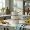 Set of three cream saucepans with lids stacked on kitchen counter