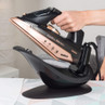Cordless rose gold steam iron on charging base, hand holding handle