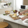 Cheese board with assorted cheeses, nuts, bread and fruit on kitchen counter