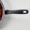 Non-stick frying pan with black handle, partially filled with tomato-based sauce