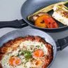 Non-stick frying pans shown with cooked eggs in tomato sauce and grilled vegetables, for product listing.