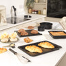 Kitchen scene with black non-stick bakeware holding croissants, bread and pastries.