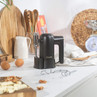 Black and gold hand mixer on kitchen counter with baking ingredients and utensils