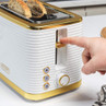 White and gold toaster in use, featuring two slices of seeded bread in kitchen setting