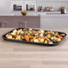 Black oven tray with roasted mixed vegetables on kitchen worktop