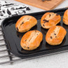 Six chocolate chip brioche rolls on a black baking tray