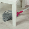 Grey spot pattern mop with pink handle cleaning under white table on light wood floor
