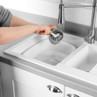 Person cleaning a bowl with a brush under running tap water at a white kitchen sink