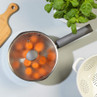 Saucepan with glass lid steaming orange tomatoes on a kitchen worktop