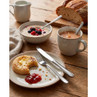 Breakfast set with porridge, berries, tea, crumpet with butter and jam on wooden table
