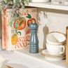 Salter grey pepper mill on kitchen shelf beside cookbooks and stacked cream bowls