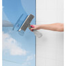 Spray bottle and sponge cleaning window with blue sky reflection