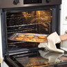 Tray of chocolate chip cookies being removed from an oven with an oven glove