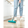 Person using a blue rubber broom to scrub wet kitchen floor