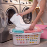 Person placing folded towels into washing machine from a laundry basket