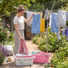 Woman hanging washing on rotary clothes airer in garden